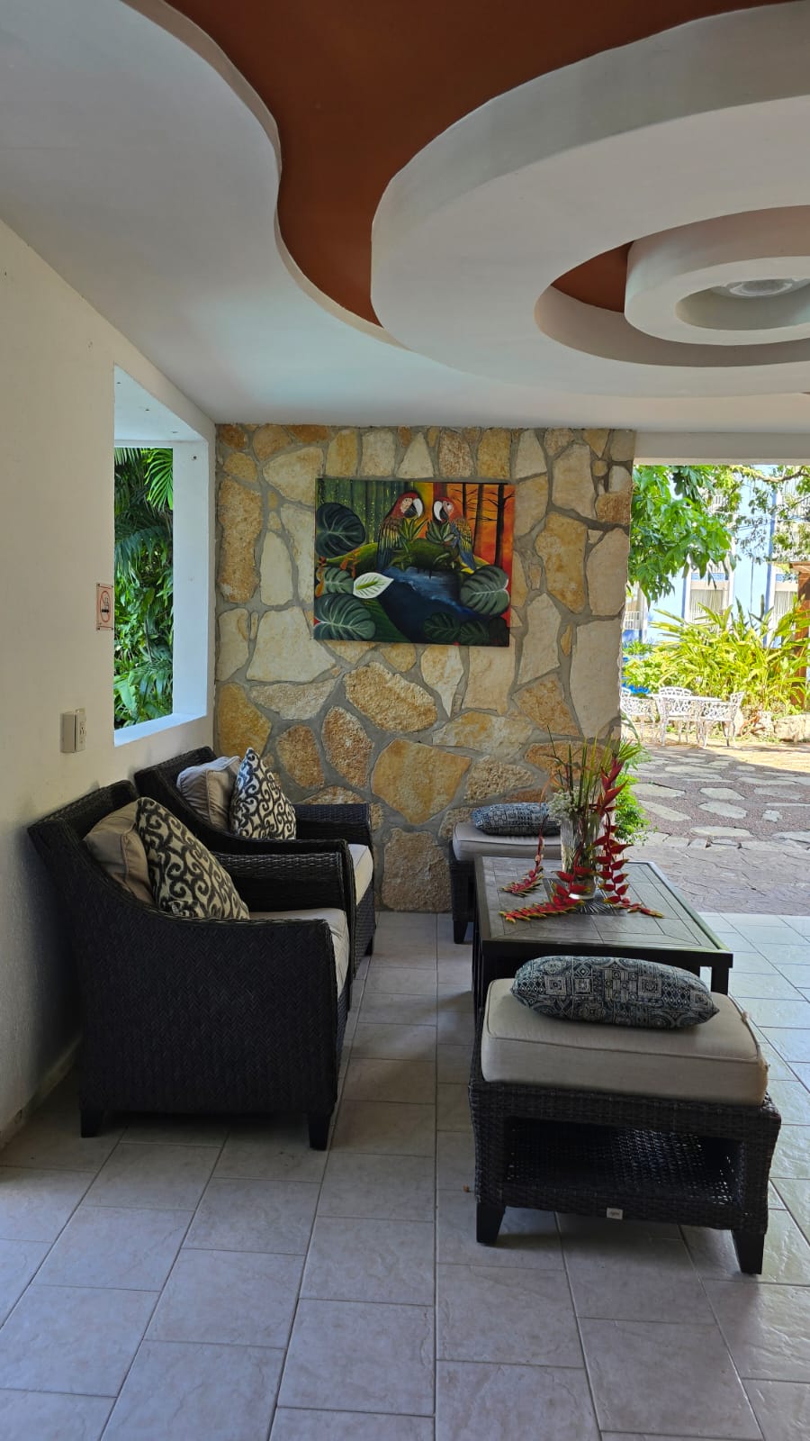 Sala de estar con piedra natural, arte tropical y vegetacion